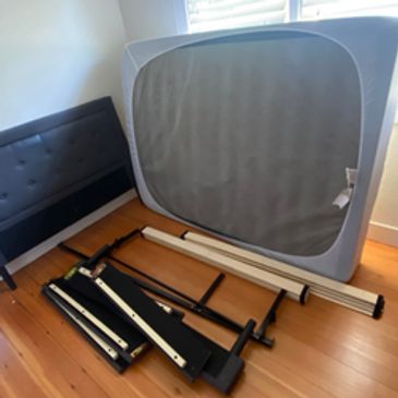 Disassembled bed frame and mattress ready for pickup and junk removal service.