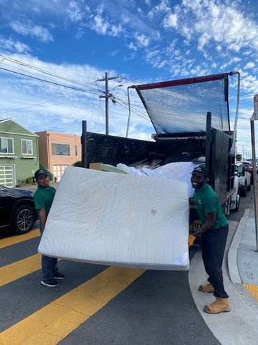 Two team members removing a mattress and putting it in a truck