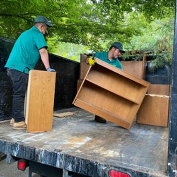 two junk removals arrange office desk in a junk truck.