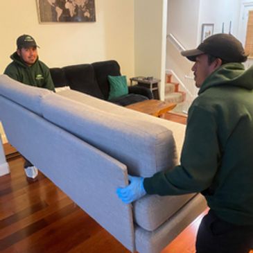 Two junk removal specialists lifting a sofa during a professional furniture removal service.