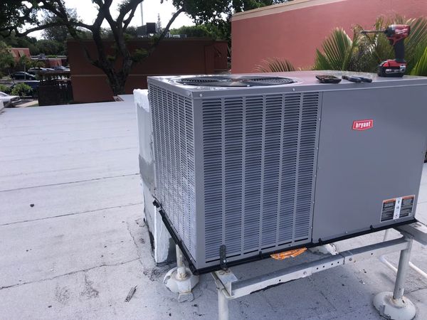 Commercial HVAC unit installed on a rooftop with tools on top.