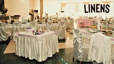 Elegant banquet hall with satin-covered chairs and tables, decorated for a formal event.