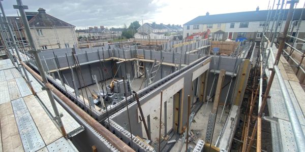 Construction site with scaffolding and building materials under a cloudy sky.