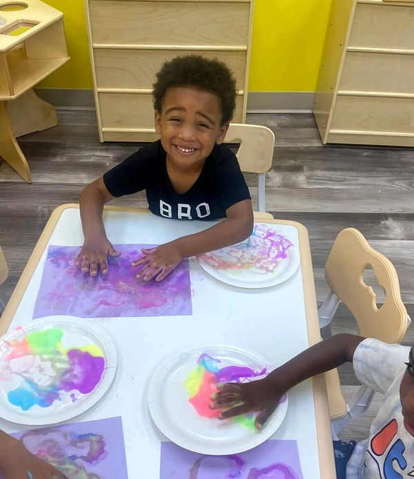 A young boy fingerpaints and smiles in Erie, Pennsylvania.