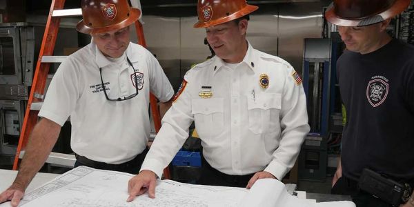Three firefighters examining blueprints together.