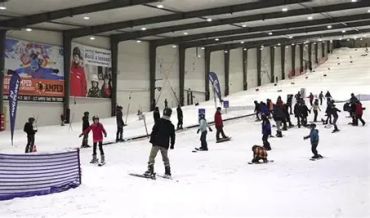 Indoor snowboarding and skiing area with people practicing.