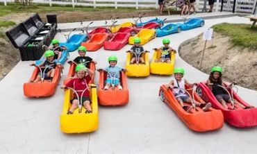 Children ready for outdoor go-kart rides wearing helmets.