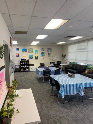 Bright, cozy room with tables, chairs, and colorful wall art.