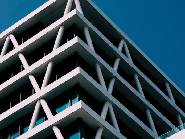 Modern building with distinctive X-shaped white supports against a clear blue sky.