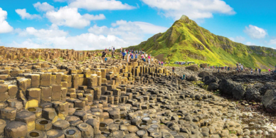Tourists explore the unique basalt columns at Giant's Causeway under a vivid blue sky.