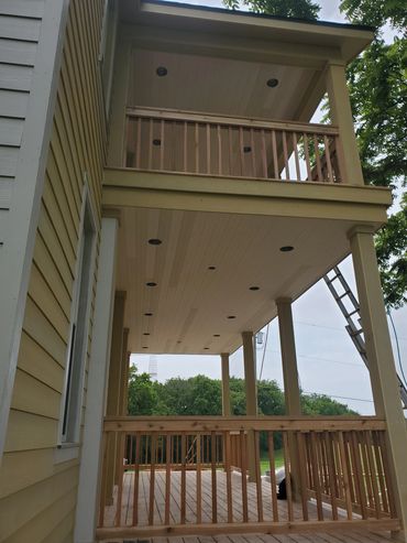 Two-level wooden porch with cedar railings, tongue and groove ceiling, recess can lights.