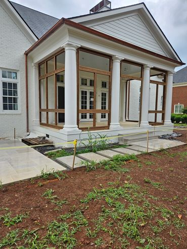 A porch under construction with white columns and wooden framework on a cloudy day.