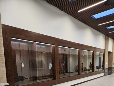 Empty glass display cases with wooden frames in a hallway.