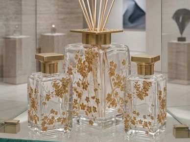 Elegant glass perfume bottles with golden floral designs and square golden caps.