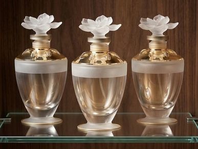Three elegant glass perfume bottles with white flower-shaped stoppers.