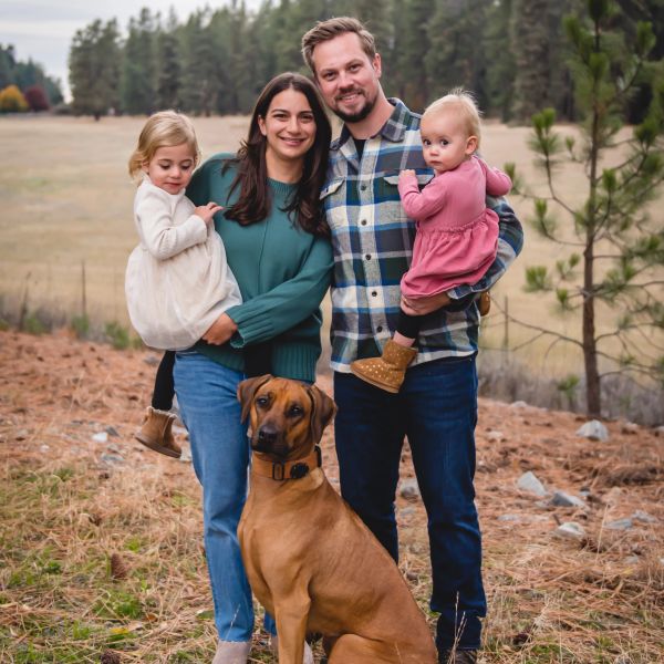 Family portrait outdoors with two children and a dog.