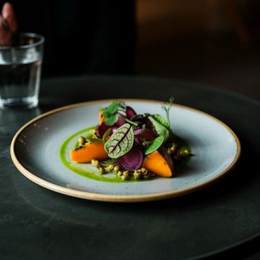 A gourmet vegetable dish artfully plated with vibrant colors and fresh greens.