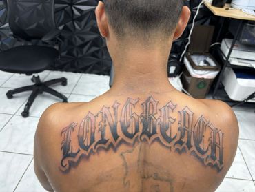 Back view of a person with a large tattoo and a black chair in the background.