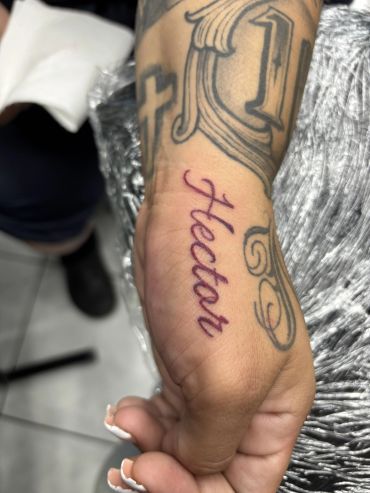 Fresh 'Heather' tattoo on wrist surrounded by other tattoos.