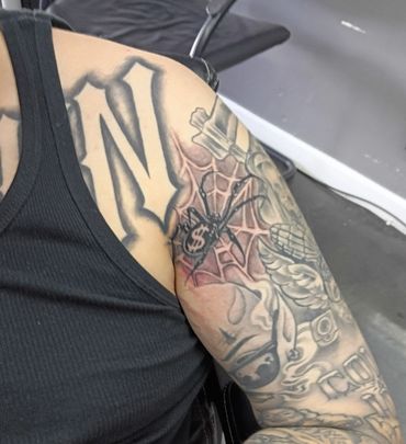 Close-up of a tattooed arm with spider and web design.