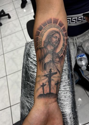 Religious tattoo of Jesus and the crucifixion on forearm.