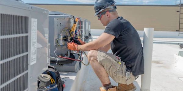 Technician repairing an HVAC unit on a rooftop.