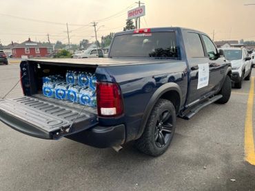 Pickup truck loaded with cases of bottled water in the bed.