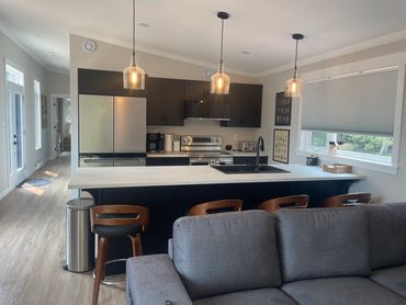 Modern kitchen with black cabinets, pendant lights, and wooden stools.