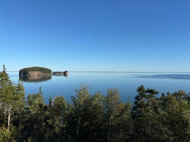 Tranquil lake with small islands and clear blue sky.