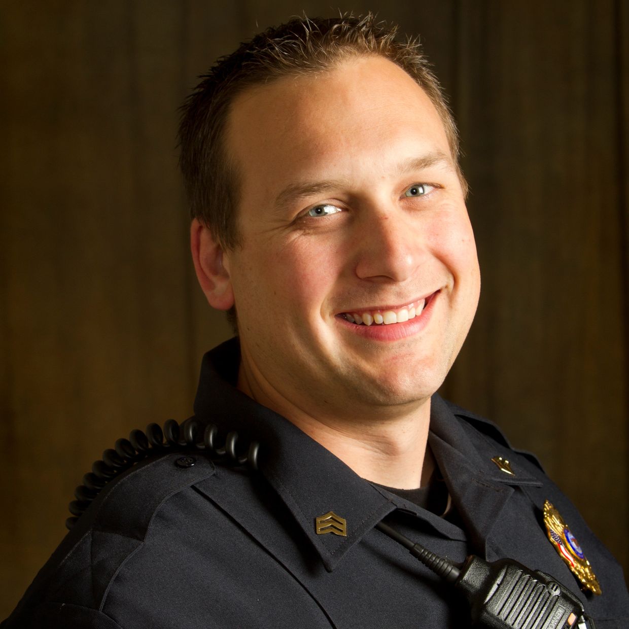 Smiling Sturgeon Bay police officer in uniform with badge and radio.
