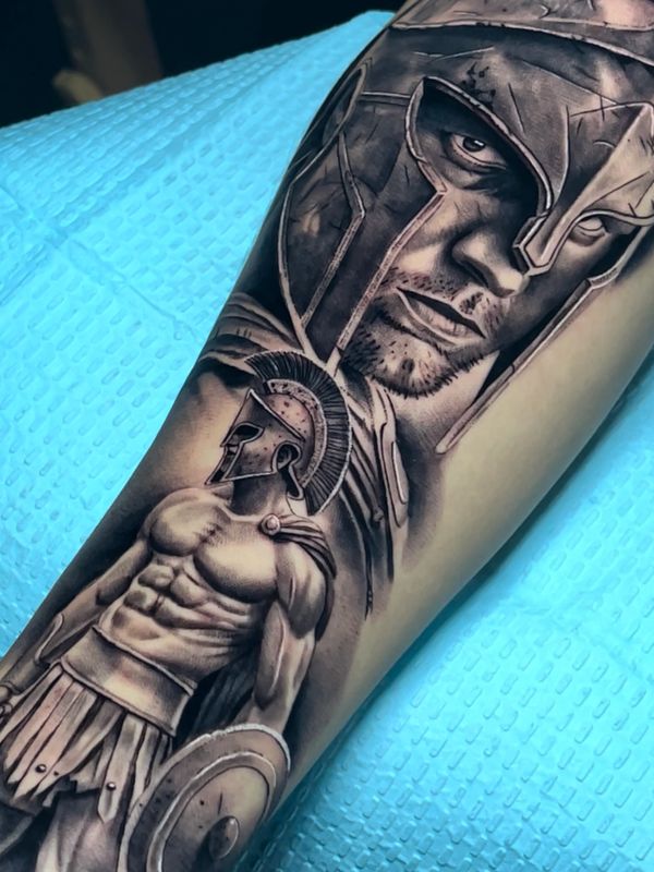 Detailed tattoo of a Spartan warrior with helmet and shield on forearm.