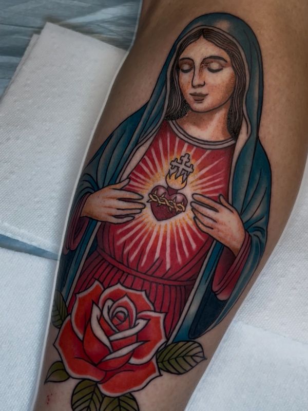 Tattoo of the Virgin Mary with a glowing heart and a red rose below.