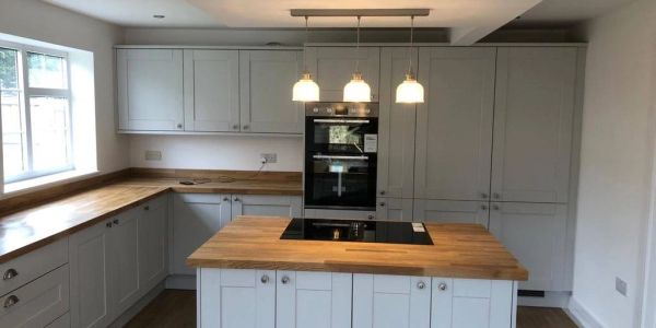 Modern kitchen with wooden countertops and white cabinets.