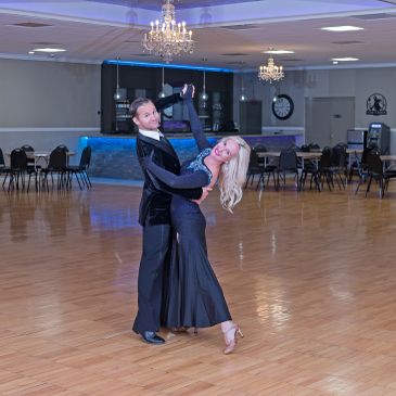 Couple performing a ballroom dance pose in a ballroom.