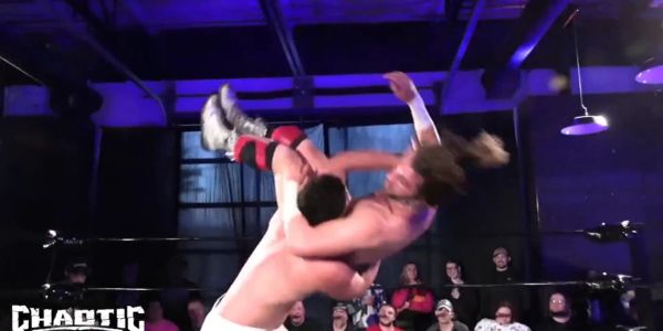 Wrestler executing a high-flying move inside a ring with an audience.