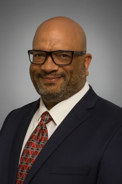 Smiling man in a suit and tie with glasses.