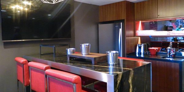 Modern kitchen with red chairs and black marble island.