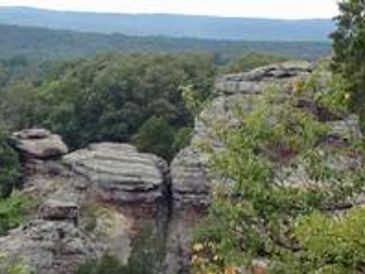 Rock formations surrounded by forest and hills.