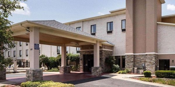 Exterior view of a hotel entrance with a covered driveway and stone accents.