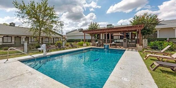 Outdoor swimming pool with lounge chairs and shaded seating area.