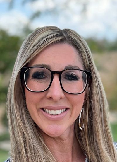 Smiling woman with blonde hair outdoors.