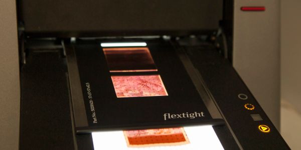 A scanner digitizing a photographic slide labeled 'flextight'.