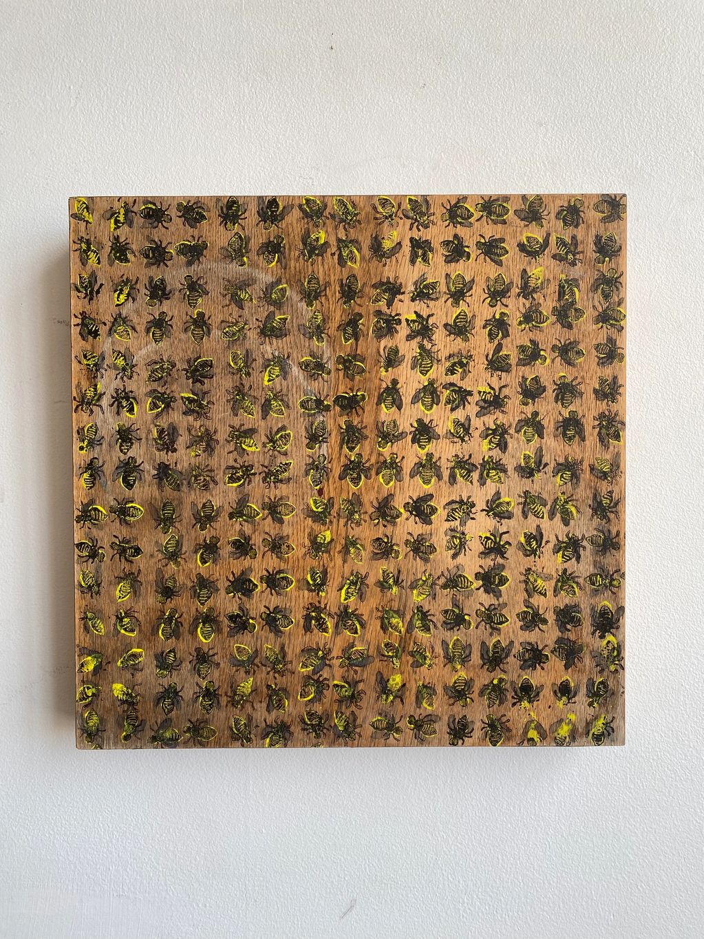 Wooden panel with rows of painted bees in black and yellow.