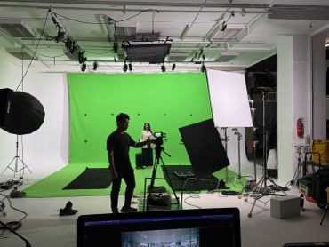 Photo studio setup with green screen and lighting.