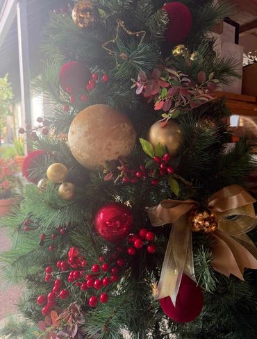 Closeup Christmas tree in law firm office featuring XL velvet baubles and berries with red & gold.