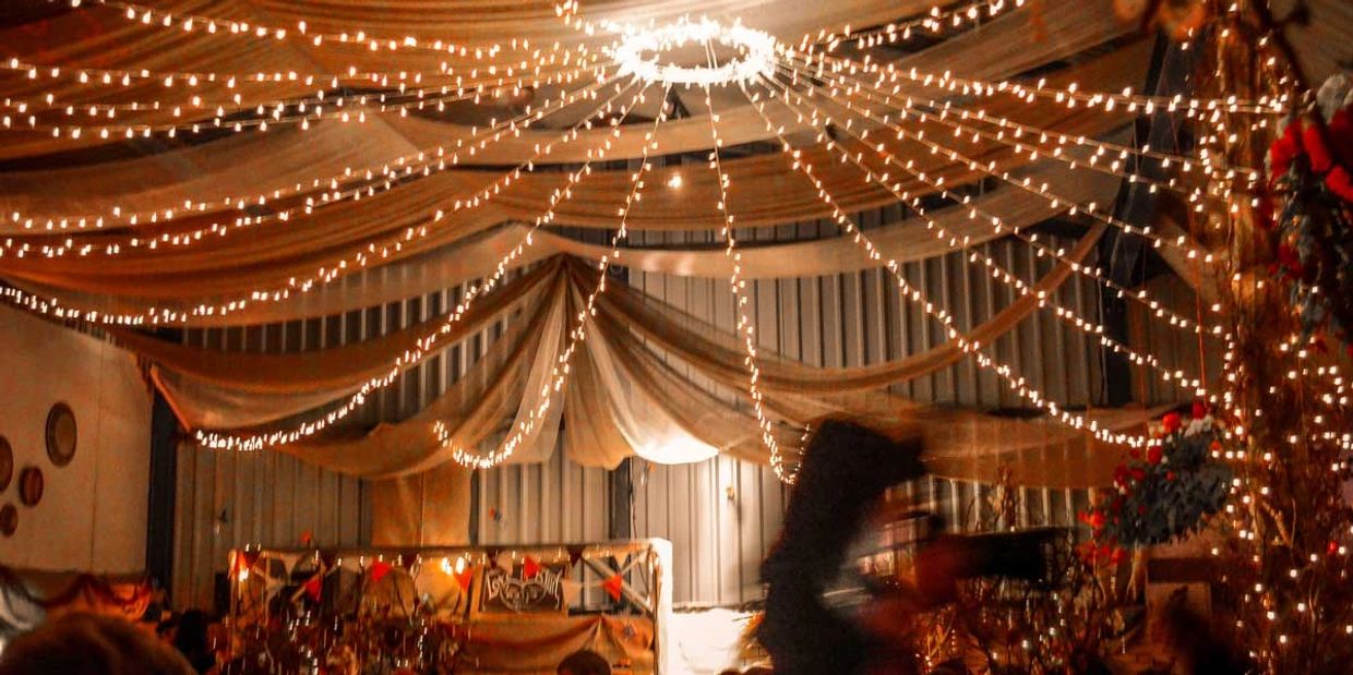 Fairy light strings and grand curtains hanging from ceiling at event.