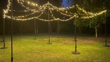 Outdoor fairy light canopy with black poles and commercial grade fairy lights in warm white.