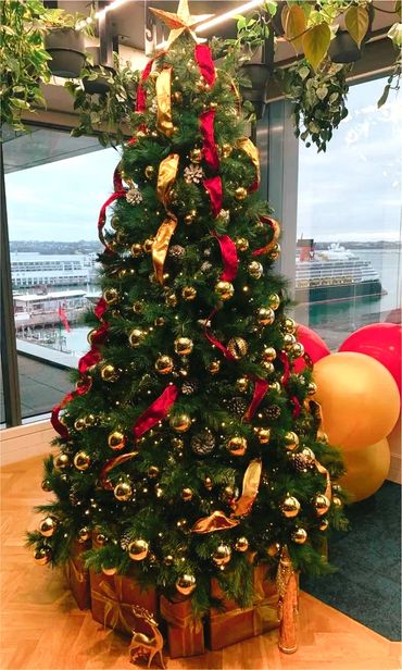 Velvet ribbon, metallic baubles and frosted pinecones on Christmas tree at end of year party.