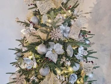 Closeup of Christmas tree with fancy mesh ribbon, berries, snowflakes and poinsettia.