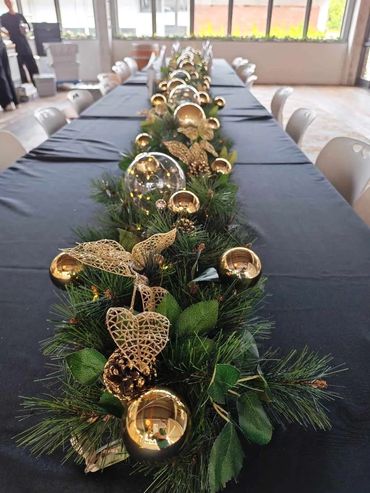 Christmas table garland featuring glass light spheres, gilded pine cones and metal spheres.